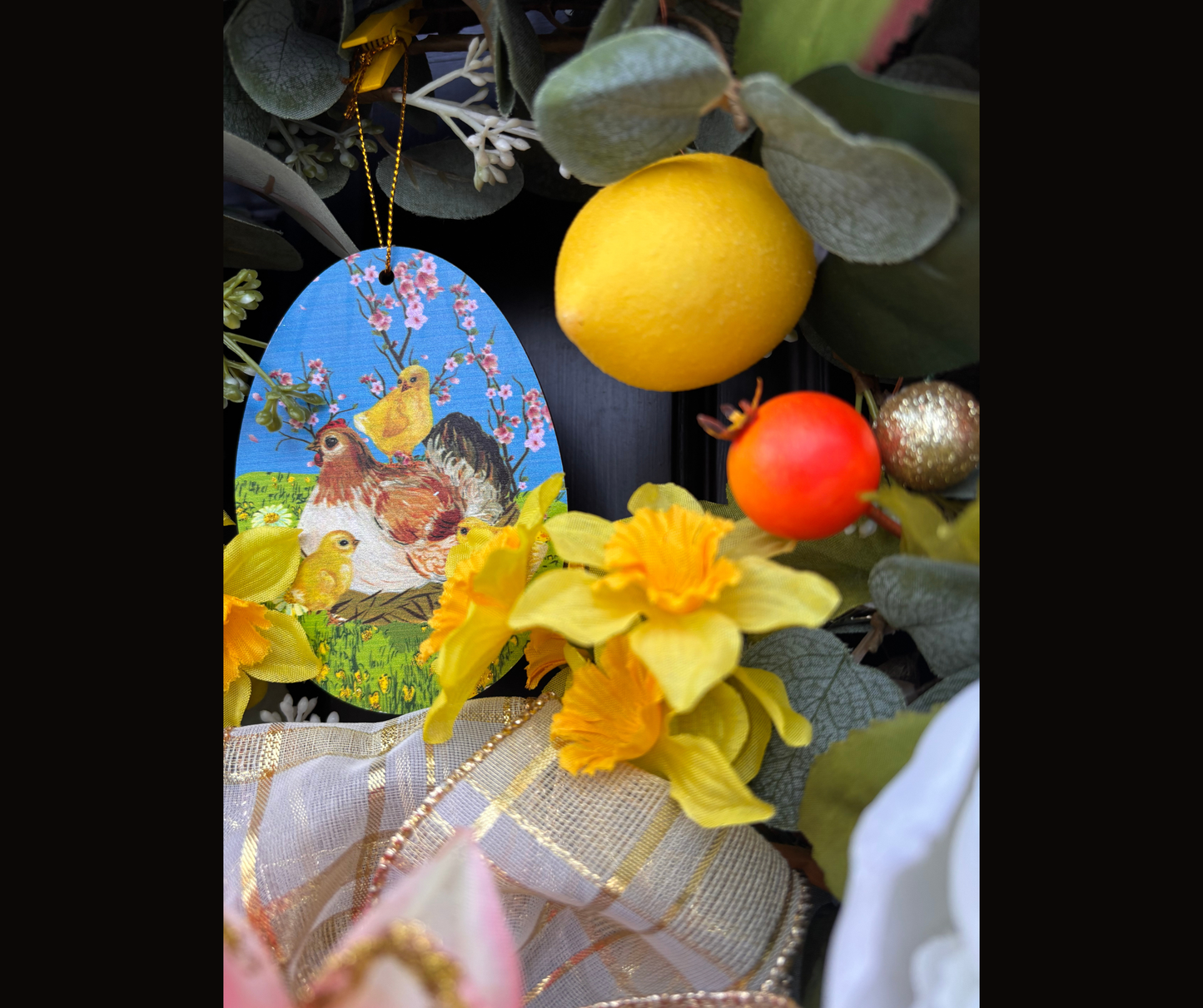 Decorative Easter egg ornament with chickens and flowers, surrounded by lemon and daffodils.